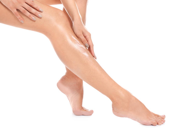 Жінка наносить крем для тіла на ногу на білому тлі, крупним планом
 - Фото, зображення