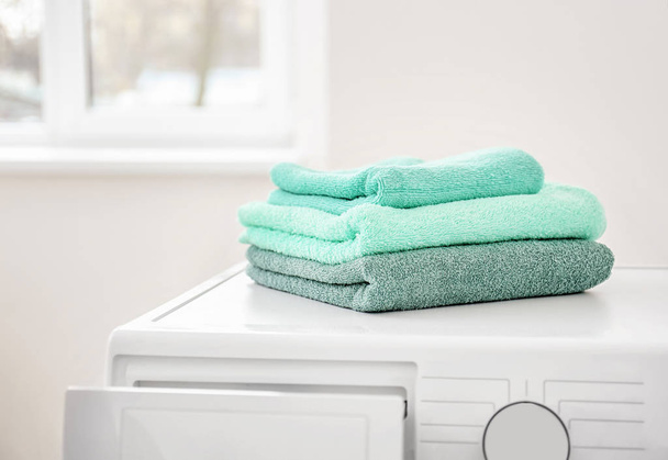 Stack of clean towels on washing machine in laundromat - Foto, imagen