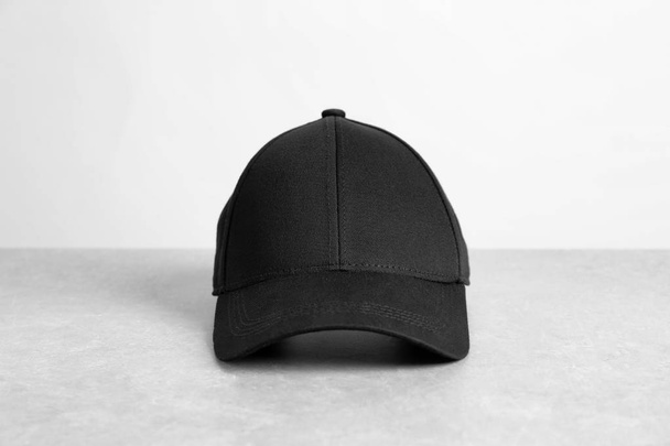 Black cap on table against white background. Mockup for design - Фото, зображення