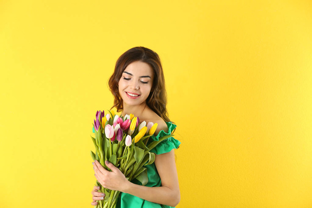 Beautiful woman holding bouquet of tulips on color background - Foto, Imagem