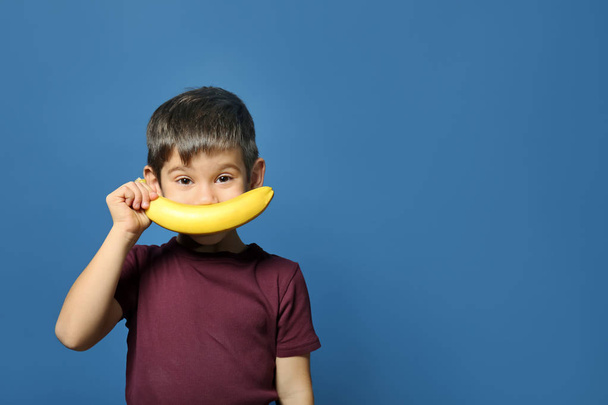 Funny portrait of cute little boy with banana on color background - Valokuva, kuva