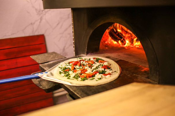 Putting traditional pizza into oven at restaurant kitchen - Photo, Image