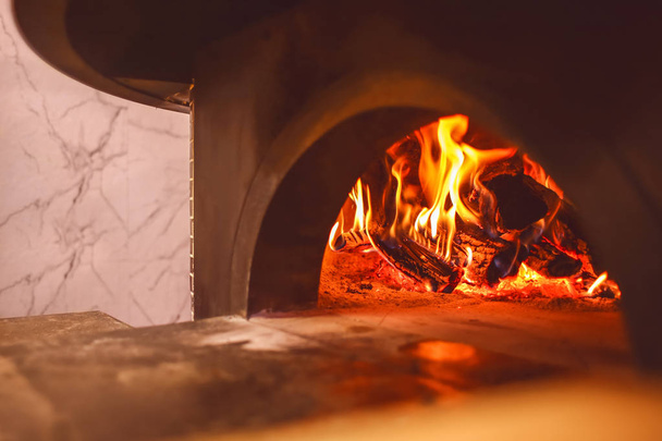 Burning firewood in traditional oven at restaurant kitchen - Zdjęcie, obraz