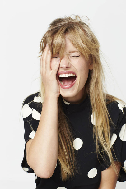 Screaming blond woman in spotted clothing, studio - 写真・画像