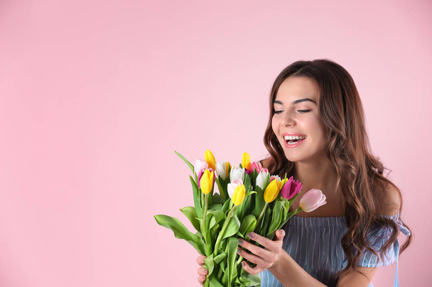 Beautiful woman holding bouquet of tulips on color background - Fotoğraf, Görsel