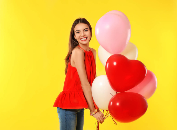 Romantic young woman with heart-shaped balloons for Valentine's Day on color background - Foto, immagini