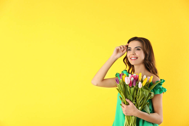 Beautiful woman holding bouquet of tulips on color background - Foto, afbeelding