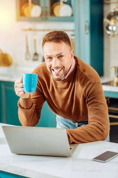 Cheerful bearded man standing in front of the laptop - Foto, Imagem