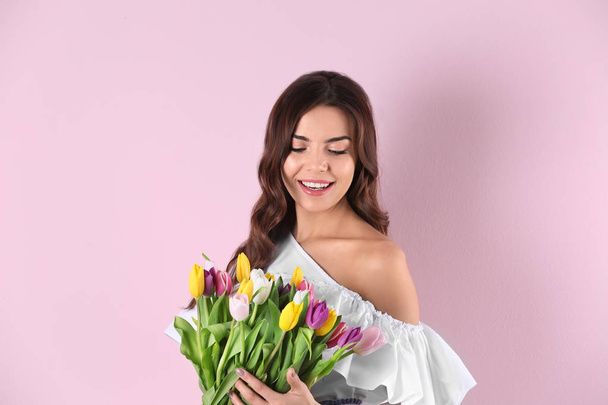 色の背景上チューリップの花束を持った美しい女性 - 写真・画像