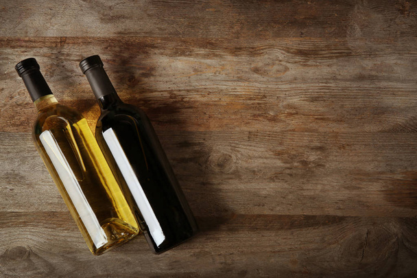 Two bottles with red and white wine on wooden background - Valokuva, kuva