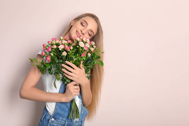 Beautiful young woman with bouquet of roses on color background - Foto, imagen