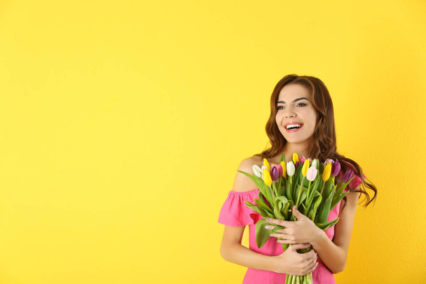 Beautiful woman holding bouquet of tulips on color background - Foto, Imagen