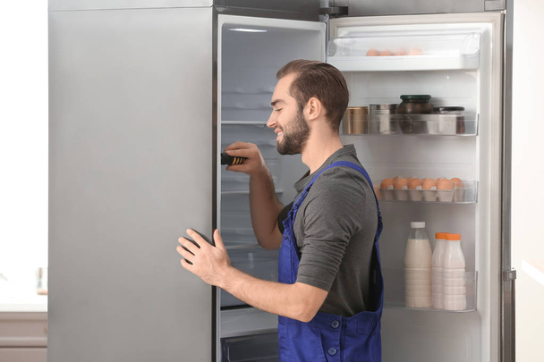 Male technician repairing refrigerator indoors - Foto, Imagen