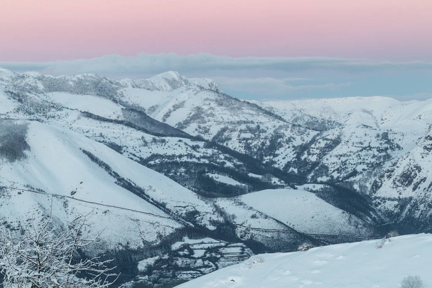 восход солнца в горах Убина, между Астурией и Леоном, в зимний день с большим количеством снега, рано утром, чтобы сфотографировать уникальные цвета первых солнечных лучей, контрастирующих со снегом, облаками и горой
 ... - Фото, изображение