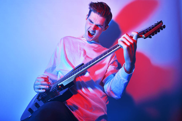 Retrato del joven artista cantando, gritando, tocando la guitarra eléctrica Hobby, concepto de música. Estrella de rock
 - Foto, imagen