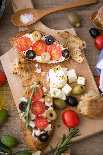 healthy Mediterranean vegetarian bruschetta on wooden cutting board with vegetable - Фото, изображение