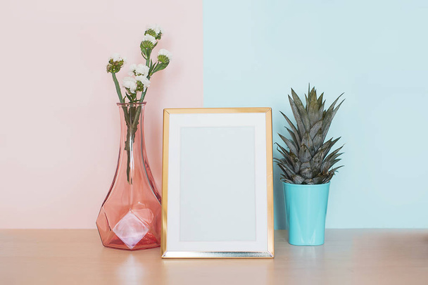 Modern home decor mock up with gold blank photo frame, vase and tropical plant on pink blue background - Foto, afbeelding