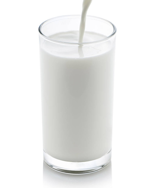 Melk van een kruik gieten in een glas op witte achtergrond - Foto, afbeelding