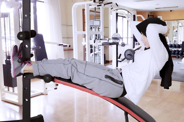 Muslim woman doing sit ups in gym center - Фото, изображение