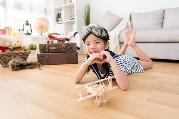 happy girl as pilot playing with wooden airplane - Фото, зображення
