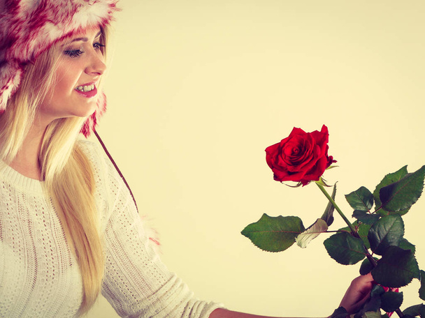 Woman in winter furry hat holding red rose - Foto, Bild