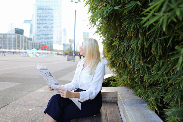 Lady reading newspaper outdoors in   with close up face. - 写真・画像