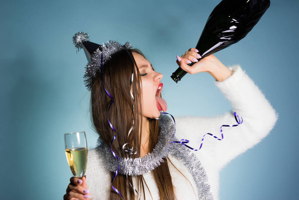 drunk woman in a festive hat holds a bottle in her hand - Foto, Imagem