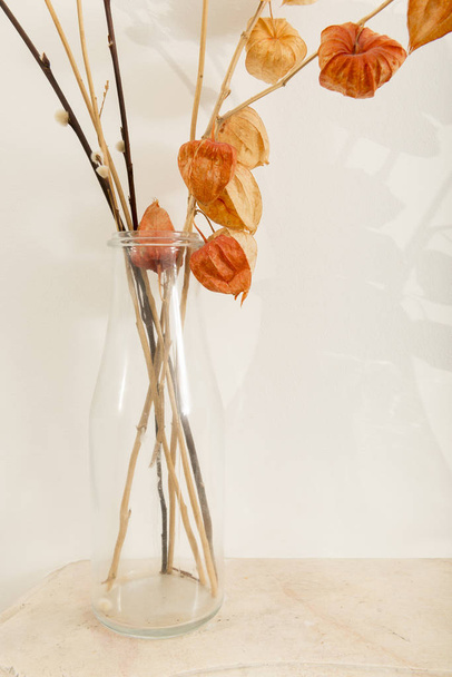 白い背景の上のしおれた花を含む明確なガラスつぼ - 写真・画像
