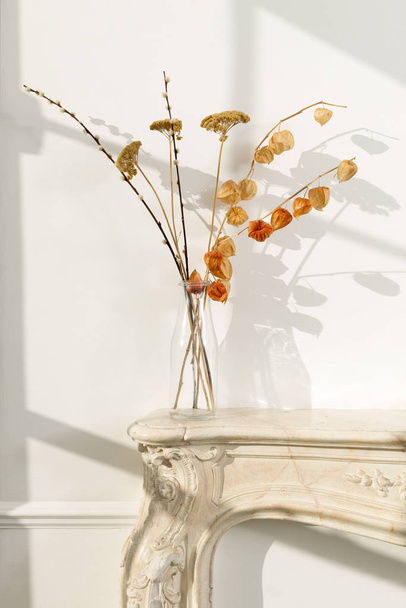 Tiszta üveg váza, hervadt virágok egy kandalló - Fotó, kép