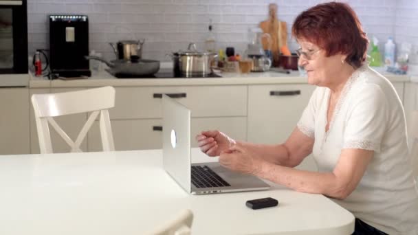 Stara kobieta porozmawiać z jej wnuczka na skype za pomocą laptopa - Materiał filmowy, wideo