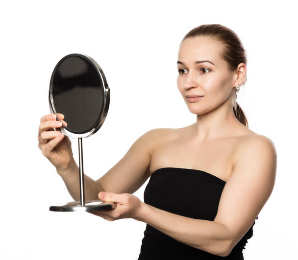 young woman performs anti-aging exercises. face fitness. girl looks in the mirror - Photo, image