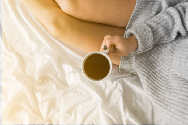 Měkká fotografii ženy na posteli s tabletem a šálek kávy v rukou, pohled shora bod kopie prostoru horní pohled žluté světlo tónování - Fotografie, Obrázek