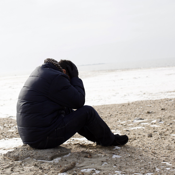 eenzame man zittend op zand - Foto, afbeelding