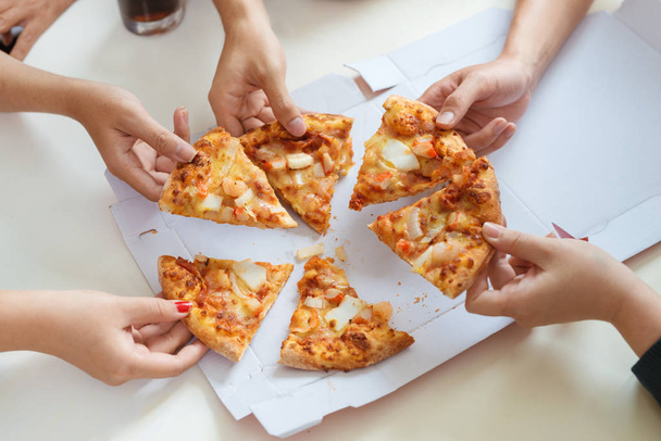 People eat fast food. Friends hands taking slices of pizza - Foto, afbeelding