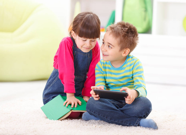 Little boy and girl playing or reading from tablet - Foto, Bild