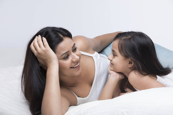 Madre e figlia si guardano mentre si rilassano a letto
 - Foto, immagini