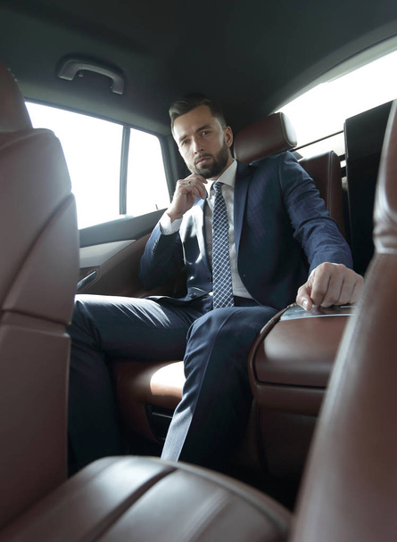Succesvolle zakenman zitten op de achterbank van een auto - Foto, afbeelding