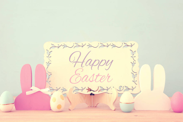 Cute colorful wooden bunny ears and easter eggs over wooden table. - Valokuva, kuva