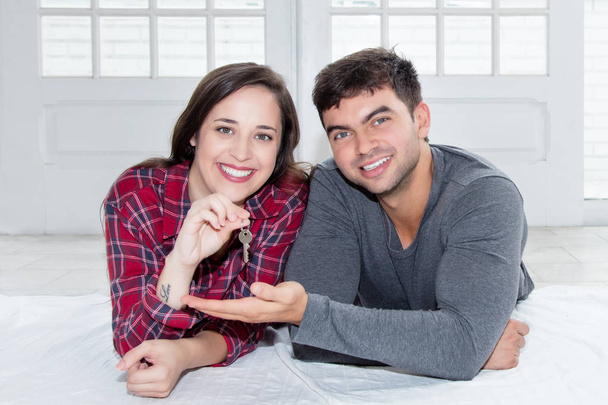Cheerful caucasian couple with key of new home - Foto, afbeelding