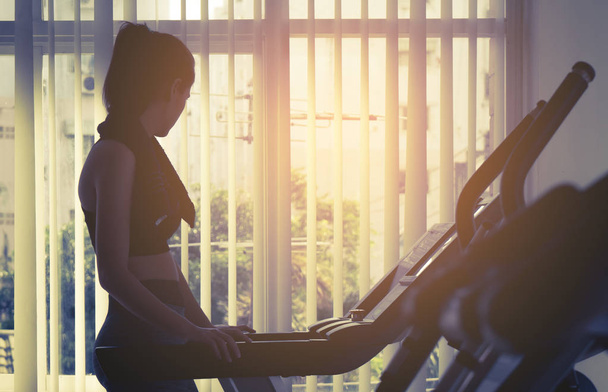 Woman working out on treadmill machine in fitness gym - Photo, Image