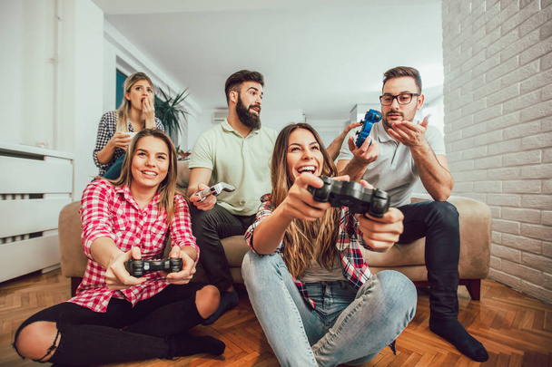 Група друзів грають у відеоігри вдома, розважаючись
. - Фото, зображення