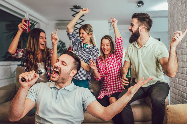 Group of friends playing karaoke at home. Concept about friendsh - Фото, изображение