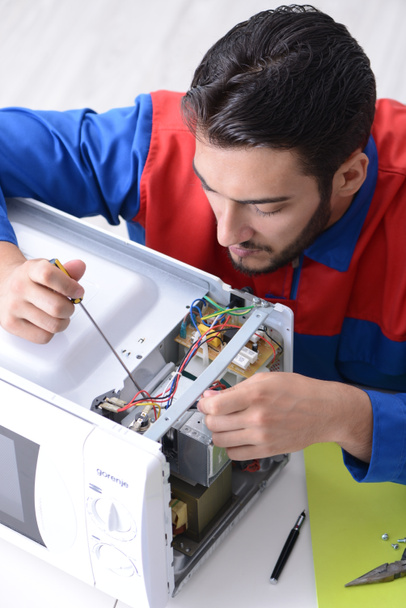 Young repairman fixing and repairing microwave oven - Photo, Image