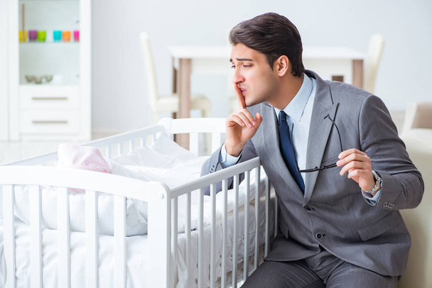 Jonge zakenman probeert te werken vanuit huis zorg na pasgeboren baby - Foto, afbeelding