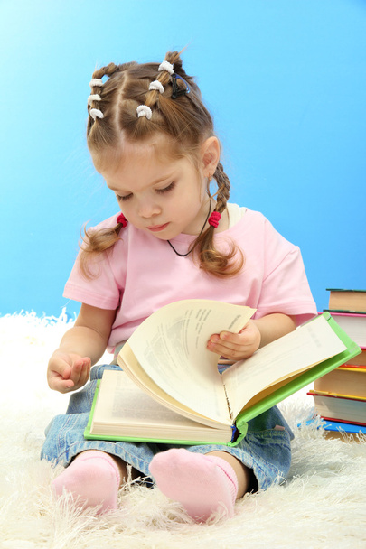 cute little girl with colorful books, on blue background - Foto, Bild