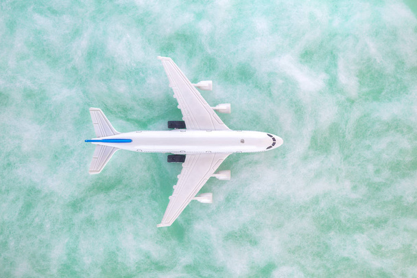 High angle view of airplane toy and clouds on green field background - Fotografie, Obrázek
