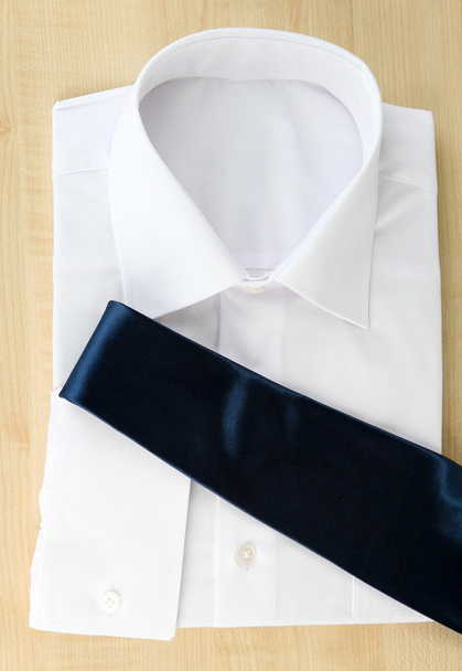 New white man's shirt with color tie on wooden background - 写真・画像
