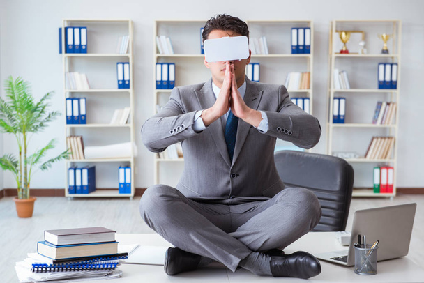 Zakenman in virtual reality VR bril mediteren op bureau top - Foto, afbeelding