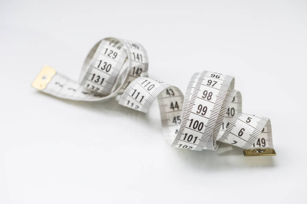 Curved measuring tape. Measuring tape of the tailor. Closeup view of white measuring tape - Photo, Image