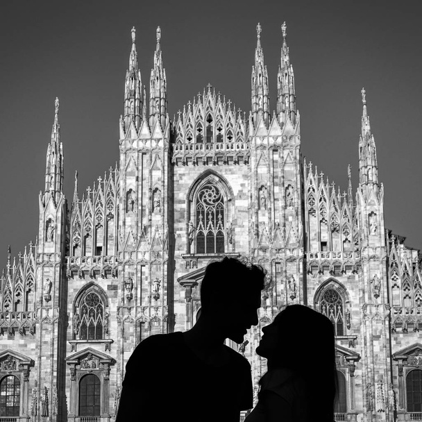 Silueta de una joven pareja besándose frente a la catedral gótica de Milán
 - Foto, imagen
